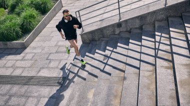 Şehir ortamında egzersiz yapmak için orta yaşlı bir adam dışarıda koşuyor. Hareket anlatısı kavramı, aktif erkek figürü, spor kimliği, günlük çalışma ritüeli ve sokak seviyesindeki dinamik.