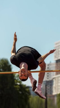 Atlet, açık hava pistinde yüksek atlama gerçekleştiriyor. Seçkin eğitim yolculuğu kavramı, sıçrama zaman çizelgesi, sağlıklı gençlik kültürü ve dayanıklılık.