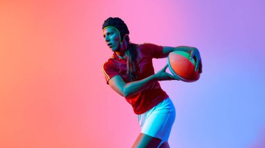 Rugby 'li kadın sporcu, canlı gradyan arka planına karşı topuyla hazır. Eylem farkındalığı, top kucaklaması kavrama ve kararlılık kavramı