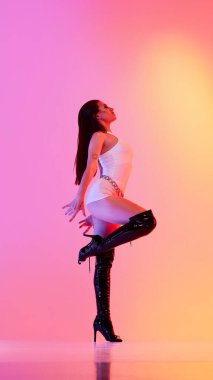 Canlı turuncu arka planda yüksek topuklu ayakkabı giyen bir kadın. Moda kampanyaları, editör dergileri, kulüp kültürü ve gece hayatı markaları kavramı