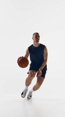 Basketbolcu sahada mavi üniforma ve beyaz ayakkabılar giyerek topu tutuyor. Kendine güvenen adımlar, dost canlısı spor tavırları, olumlu erkeklik ve yaklaşılabilir koçluk kavramı..