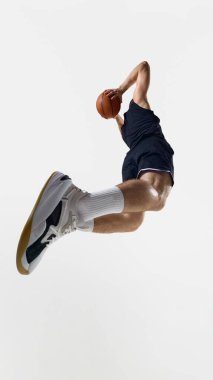 Havada basketbolcu, beyazın üzerine smaç basıyor. Uçuş süspansiyonu, vücut koordinasyonu, hareket durması ve spor ayakkabı ürünü vurguları kavramı.