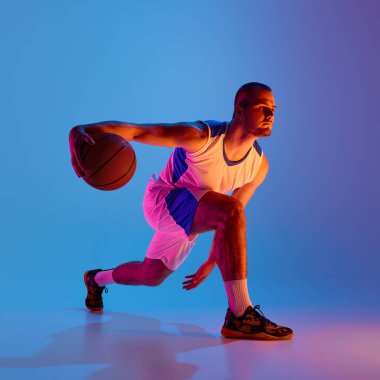 Basketbol atleti hareketli gradyan ışıklar altında salya akıtıyor. Çömelmiş güç kavramı, hazır olma, dinamik denge ve spor giyim kampanyası görselleri.