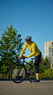 Yaşlı adam güneşli şehir sokağında bisiklete binmek için bacağını sallıyor. Fitness rutini kavramı, yaşlanmaya güven, hareket başlangıcı, kişisel sağlık, bisiklet yaşam tarzı.