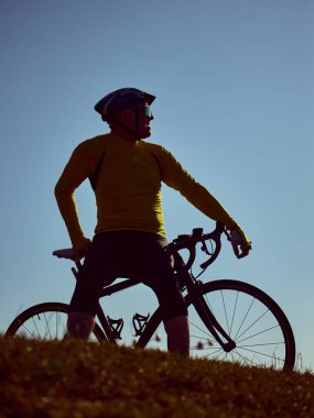 Yaşlı bisikletçi gece yarısı çimenli tepenin yanlamasına bisiklete binip yan bakıyor. Aktif emeklilik anlayışı, dayanıklılık yaşam tarzı, kıdemli fitness, ilham verici sağlık yolculuğu..