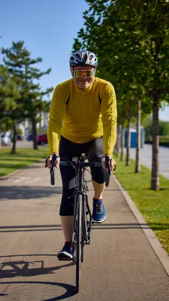 Sunny Park 'ta bisiklet sürerken gülümseyen yaşlı bir bisikletçi. Kıdemli sağlık farkındalığı, açık hava spor tanıtımı, fitness yaşam tarzı ve aktif yaşlanma motivasyonu kavramı.