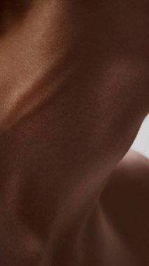 Erkek boynunun gölgesinde, tanımlanmış kas yapısı ve dokusu ile yaklaşın. Vücut kimliği kavramı, somatik farkındalık ve erkek akıl sağlığı.