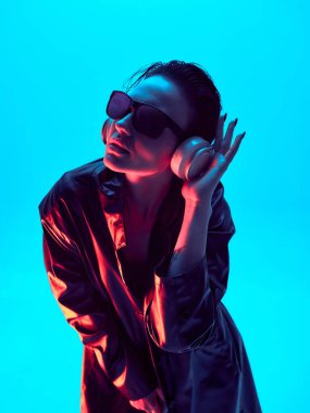 Mavi neon ışıklı kulaklıklı gelecekçi moda kadını. Ses daldırma, sanatsal gece hayatı ve müzikten esinlenilmiş görseller..