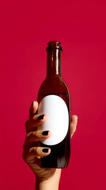 Kırmızı arka planda boş etiketli bira şişesi, markalaşma için maket. Alkol reklamı kavramı, ürün kimliği, ticari pazarlama ve tanıtım metni şablonu.