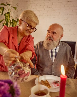 Duygusal aile ortamında çay içen yaşlı bir çift. Nesiller boyunca destek, miras, refah ve yakınlık kavramı.
