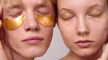 Göz altı cilt bandı takmış, gözleri kapalı, rahat genç bir çift. Farkındalık güzellik ritüelleri, rahatlama terapisi, sağlık hizmeti farkındalığı ve kozmetik ürün tanıtımı kavramı.