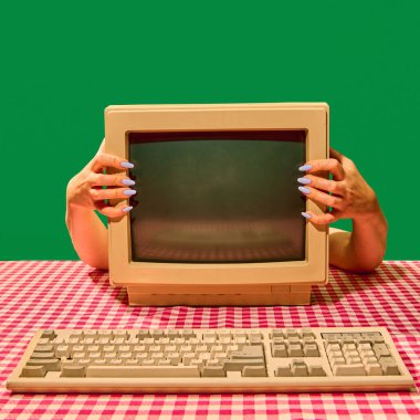 Eller masanın üzerinde klavyeli klasik bilgisayar monitörünü tutuyor. Retro teknoloji kavramı, sosyal medya ve dijital içerik, ve nostalji psikolojisi ve duyguları.