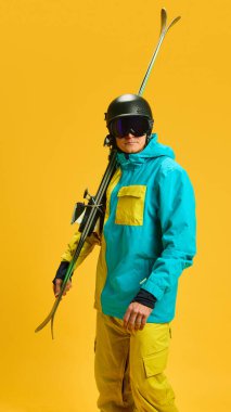 Skier with helmet and goggles resting skis on shoulder. Concept of strong visual branding, professional athlete lifestyle, advertising campaigns and winter sports promotion.