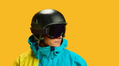 Skier close-up portrait in helmet and goggles against yellow background. Concept of winter athlete identity, professional branding visuals, gear protection awareness and editorial campaigns.