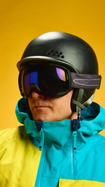 Skier portrait with black helmet and goggles on yellow background. Concept of extreme sports visuals, identity branding for winter athletes, gear protection promo and seasonal fashion advertising.