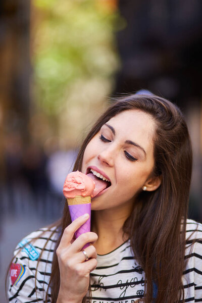 Woman licking ice cream out of cone.