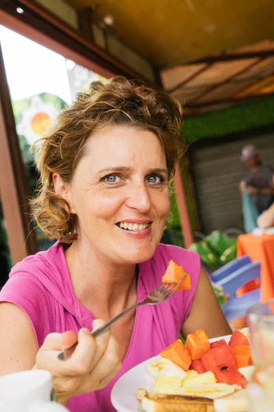 Dorosła Kobieta Jedząca Świeże Owoce Tropikalne Wyglądające Szczęśliwe — Zdjęcie stockowe