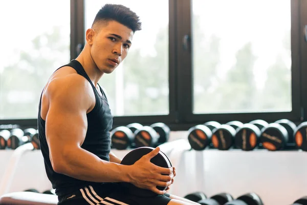 Young man working out in a gym alone.