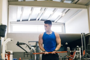 Vücut geliştiren adam spor salonunda ağırlık kaldırıyor..