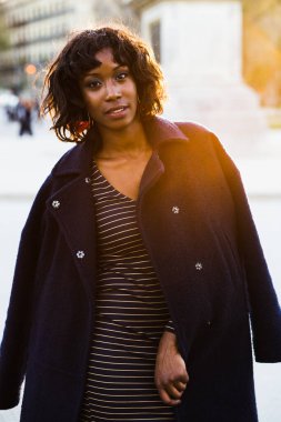 Arka planda günbatımı olan genç bir mankenin şehirde dolaşması..