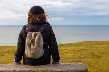 Tanımlanamayan bir kadının oturup okyanusu seyretmesi..