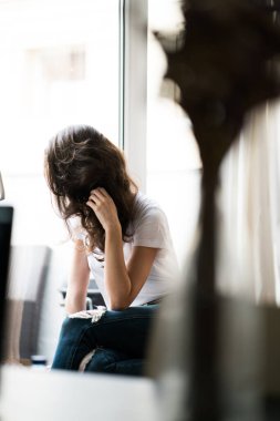 Evde oturup pencereden bakan bir kadın..