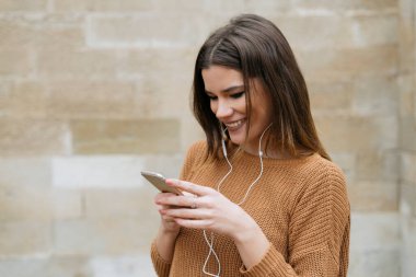 Esmer kadın cep telefonunu dışarıda tek başına mutlu bir şekilde kullanıyor.