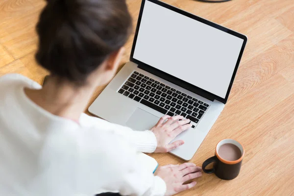 女人坐在地板上 端着一杯咖啡 在电脑上打字 — 图库照片