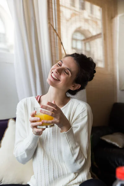 Kaukaska Kobieta Mając Sok Pomarańczowy Siedzi Kanapie Wewnątrz Uczucie Wesoły — Zdjęcie stockowe