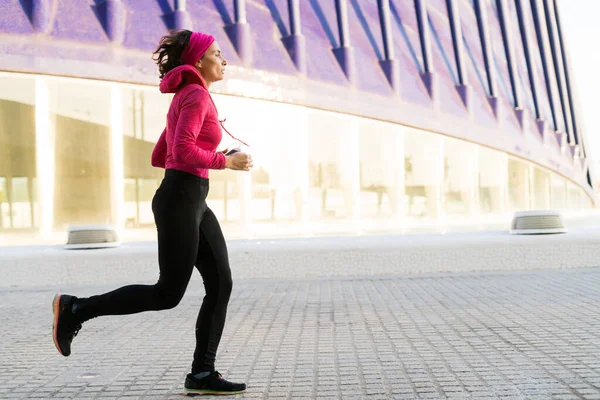 Adult woman wearing pink sport clothes jogging outdoors