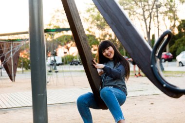 Genç İspanyol Asyalı kadın çocuk parkında oynuyor, eğleniyor ve gülümsüyor.