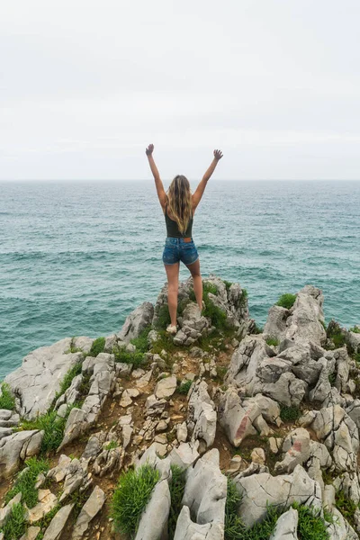 高崖の横に立っている女性の手を空に置くのレビューショットのレビュー — ストック写真