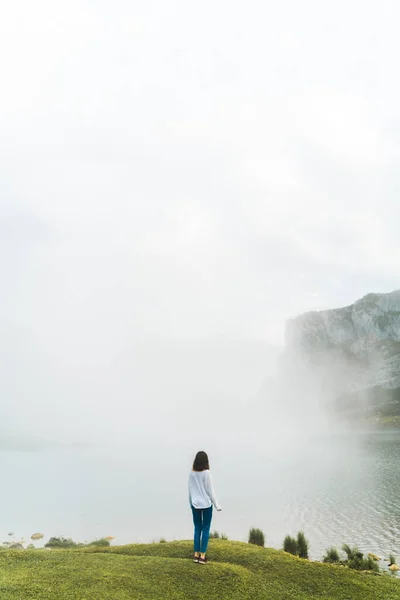 在雾蒙蒙的日子里 再看一个站在悬崖边欣赏湖景的高加索女人 — 图库照片