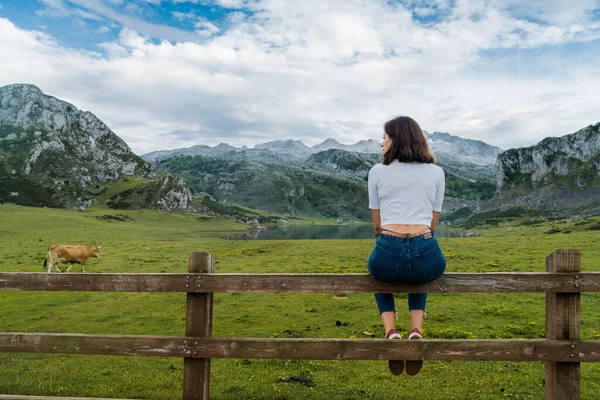 Młoda Kobieta Siedzi Płocie Ciesząc Się Widokiem Jezioro Wysokimi Górami — Zdjęcie stockowe