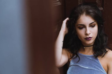 Sivri uçlu, dudağına piercing takan ve kameradan başka yere bakan genç bir kız. .