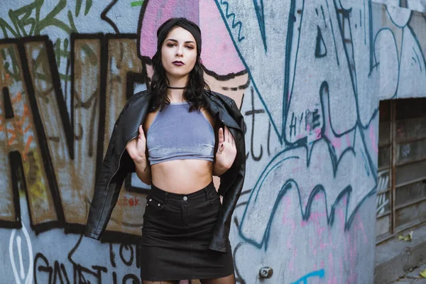 Omzunda deri ceket tutan genç bir manken kameraya şehvetli bir şekilde bakıyor..