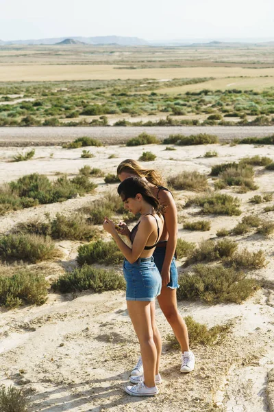 Young Couple Girls Desert Landscape Using Cellphone — Stok Foto