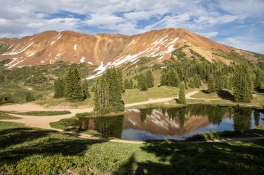 Berrak, mavi gölü olan güzel bir dağ manzarası. Bulutlu güzel mavi gökyüzü. Yaz fotoğrafı, ama buzullarda hala biraz kar var..