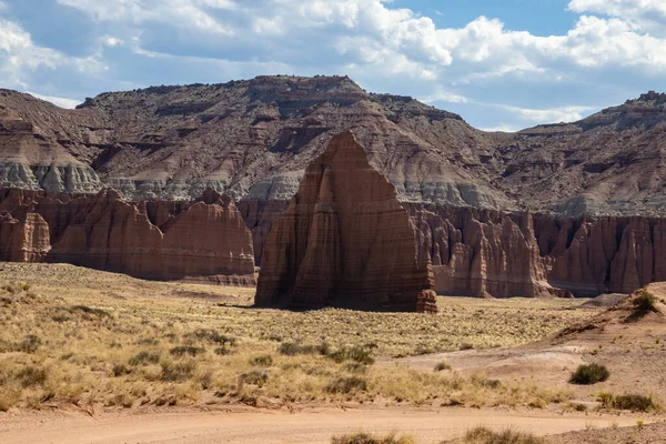 Utah, ABD 'deki Capital Reef Ulusal Parkı' nda çarpıcı kaya oluşumları. Kırmızı, turuncu ve gri taşlardan bir sürü eşsiz şekil. Ön planda çöl bitkileri. Mavi gökyüzü. 