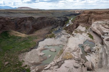 Çarpıcı bir manzara, New Mexico 'daki kayalık kanyonlardan geçen dolambaçlı nehri yakalar. Kuru arazi, doğanın güzelliğini gözler önüne seren bankalar boyunca yemyeşil alanlar ile çelişiyor..
