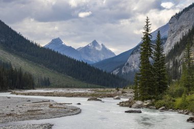 Sakin bir nehir, bulutlu bir gökyüzünün altında yükselen dağlar ve sık ormanlar tarafından kucaklanan tenha bir vadiden zarifçe akar. Doğanın güzelliği her yönde sergilenir..