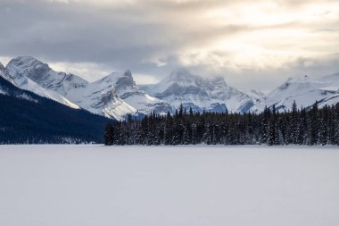 Kış öğleden sonra, heybetli dağlar ve yoğun çam ormanlarıyla çevrili donmuş bir göl manzarasını gözler önüne seriyor. Yumuşak bulutlar manzaraya atmosfer katarak huzurlu manzarayı güçlendirir..