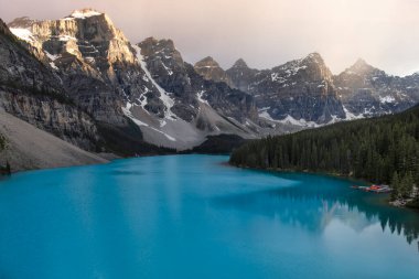Sakin turkuaz sular, yumuşak bir sabah parıltısı altında yükselen dağları yansıtır. Kıyı boyunca uzanan çam ağaçları açık hava aktiviteleri için mükemmel, sakin, doğal bir ortam yaratıyor..