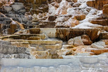 Su sersemletici mineral terasların üzerinden akar, çeşitli renklerde katmanlı oluşumlar yaratır. Jeotermal aktivite bu büyüleyici manzaraya katkıda bulunuyor, doğa meraklılarını cezbediyor..