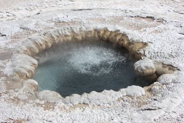 Kaynayan gayzer, Yellowstone Ulusal Parkı 'nda gün ışığında buhar yaratıyor. Mineral zengini birikintiler termal özelliğin ana hatlarını belirler, doğanın eşsiz güzelliğini gözler önüne serer..