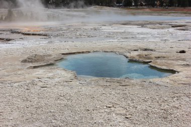 Yellowstone Ulusal Parkı 'ndaki jeotermal havuzda eşsiz mineral oluşumları ve buharlı kaplıcalarla çevrili parlak mavi sular, doğa severler ve fotoğrafçıları cezbediyor..