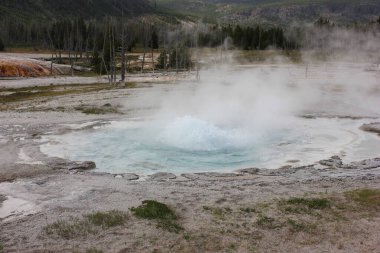 Yellowstone Ulusal Parkı 'ndaki kaynayan kaplıcadan gelen buhar dalgaları. Turkuaz su, mineral zengini buharlar salınarak bölgedeki jeotermal aktiviteyi gözler önüne seriyor..