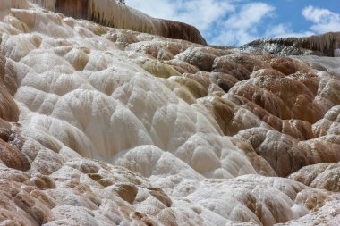 Turkuaz ve beyaz mineral yatakları, Yellowstone Ulusal Parkı 'ndaki berrak bir gökyüzünün altında güneşlenen sıcak kaplıcaların katmanlı teraslarda akması gibi karmaşık bir desen oluşturuyor..