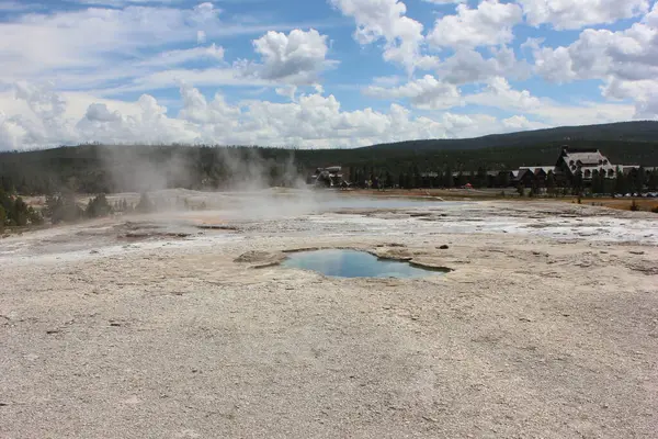 Havada dalgalanan buharı gösteren doğal jeotermal aktivitenin sakin bir görüntüsü. Küçük bir mavi su havuzu Yellowstone Milli Parkı 'ndaki yemyeşil gökyüzünü yansıtır..