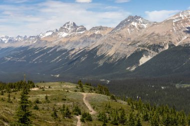 Yoğun ormanlarla çevrili uçsuz bucaksız dağ sıraları ve bereketli manzaranın içinden geçen dolambaçlı bir patika. Parlak gökyüzü bu huzurlu yerin doğal güzelliğini arttırır..